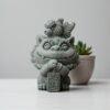 Green sandstone Foo Dog Tea Pet statue holding [Specific Item], cute Feng Shui desk ornament.